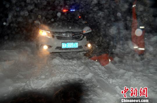 圖為消防人員跪在雪地里用鐵鍬鏟雪救援被困車輛?！±罱z
